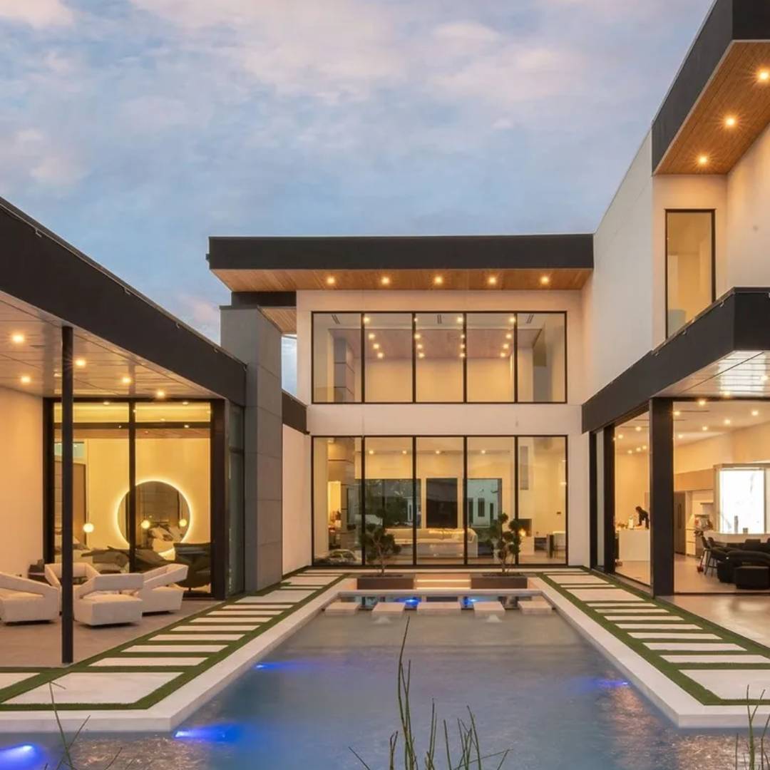 Modern luxury house with pool and evening lights.