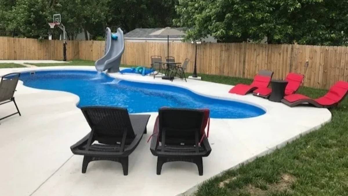 Backyard pool with slide and lounge chairs on a sunny day.